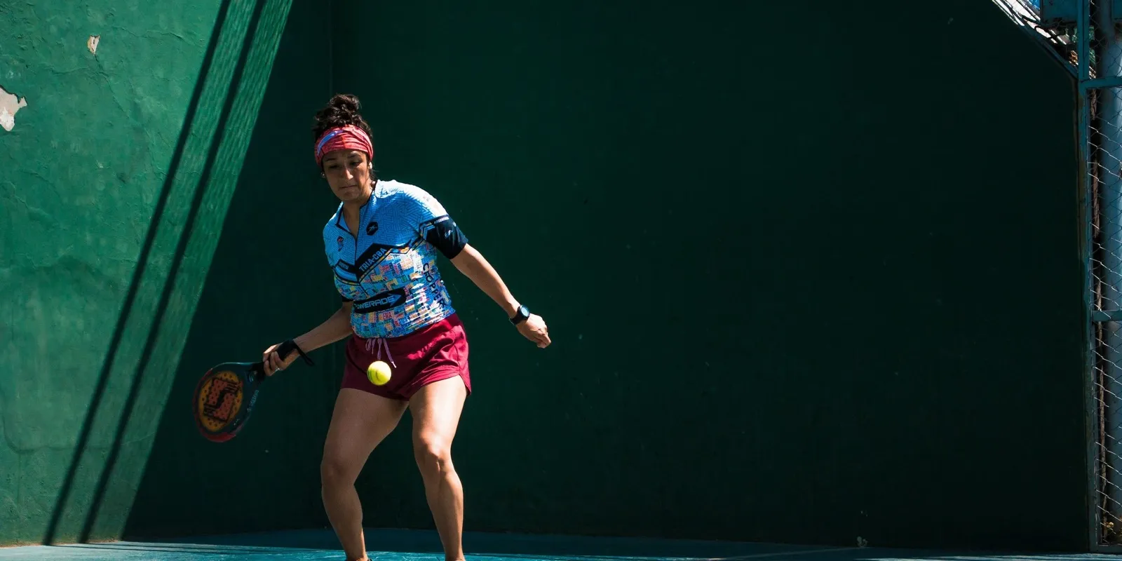 Joueuse de padel fléchie sur ses appuis pour frapper une balle basse