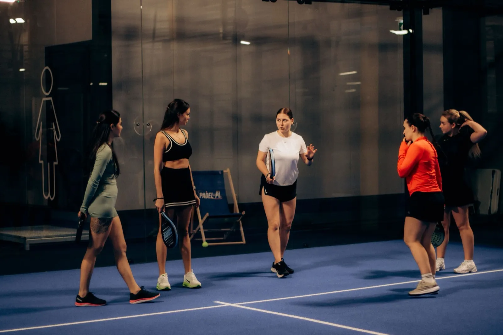 Groupe de joueuses avec leurs raquettes sur un court de padel en salle